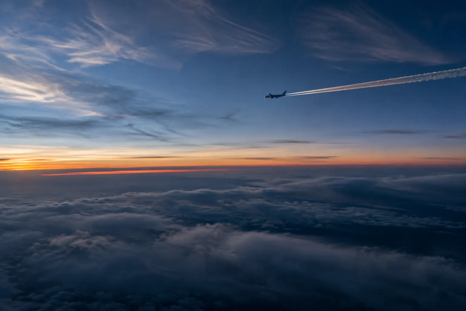 Passagierflugzeug mit langlebigem Kondensstreifen in Wolken bei Dämmerung